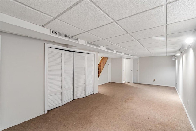 finished basement with stairway, carpet, visible vents, and a paneled ceiling