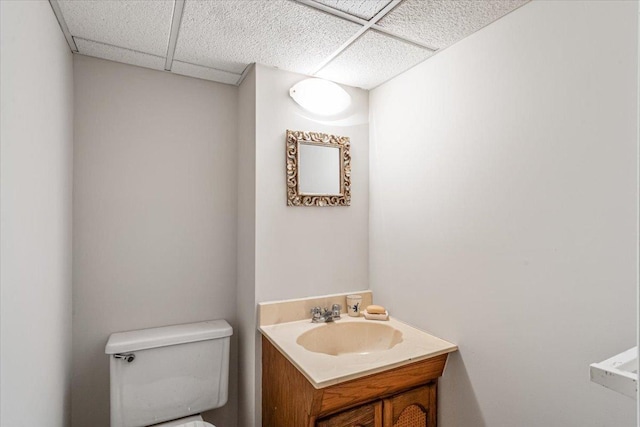 bathroom with vanity, toilet, and a drop ceiling