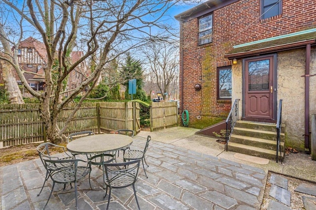 view of patio with outdoor dining space, entry steps, and fence