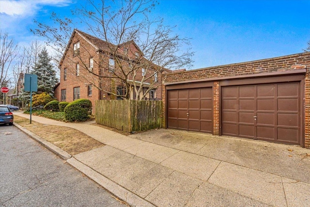 view of front of property with brick siding, a garage, and fence