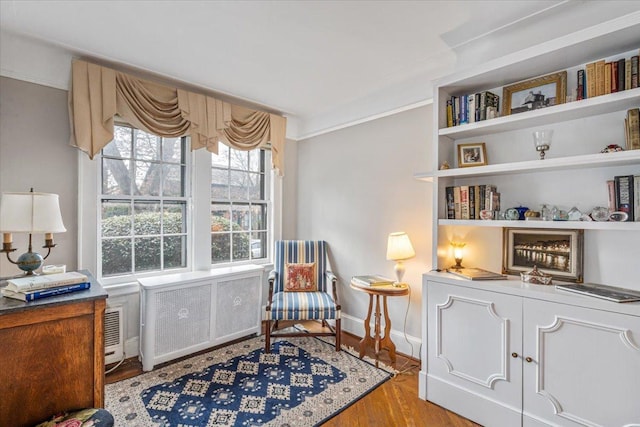 living area featuring baseboards, wood finished floors, radiator heating unit, and crown molding