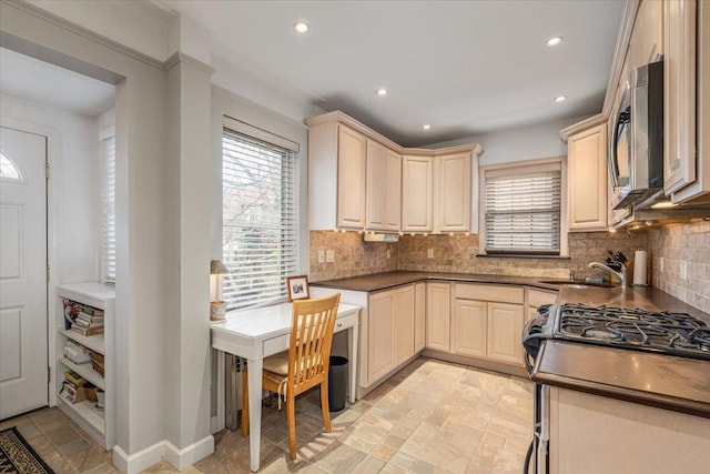 kitchen featuring a wealth of natural light, stainless steel microwave, dark countertops, and a sink