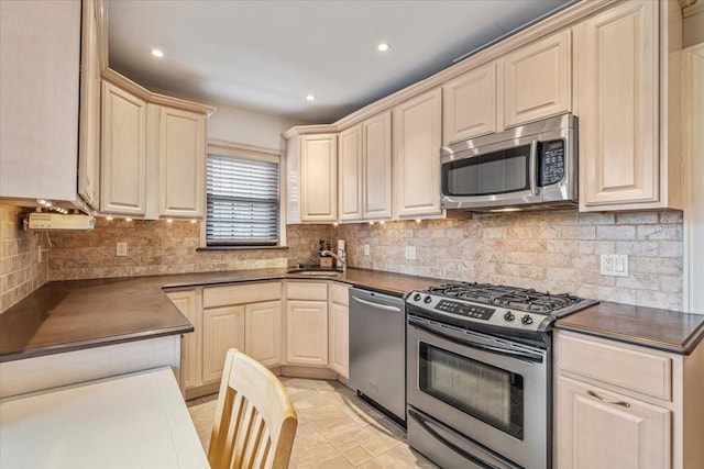 kitchen featuring a sink, dark countertops, backsplash, and stainless steel appliances