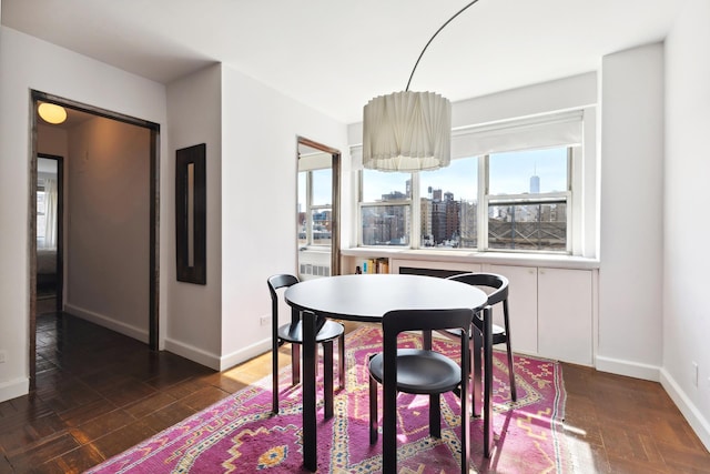 dining space featuring a city view, baseboards, and dark wood-style floors