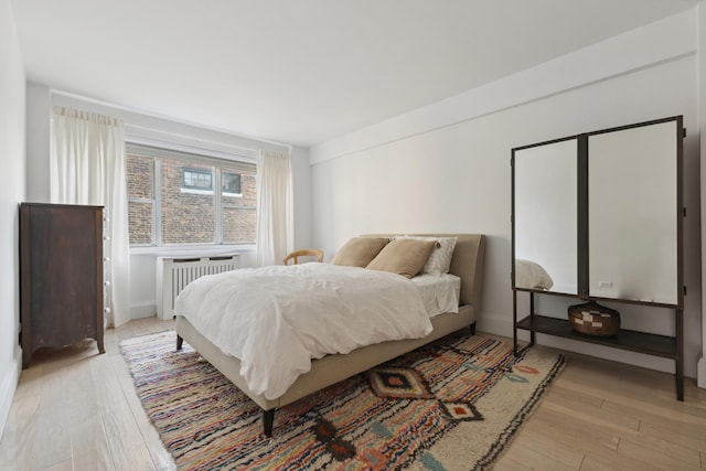 bedroom with radiator and light wood-style flooring