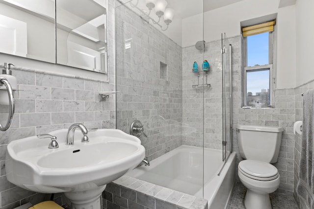 full bathroom featuring a wainscoted wall, a sink, tiled shower / bath combo, tile walls, and toilet