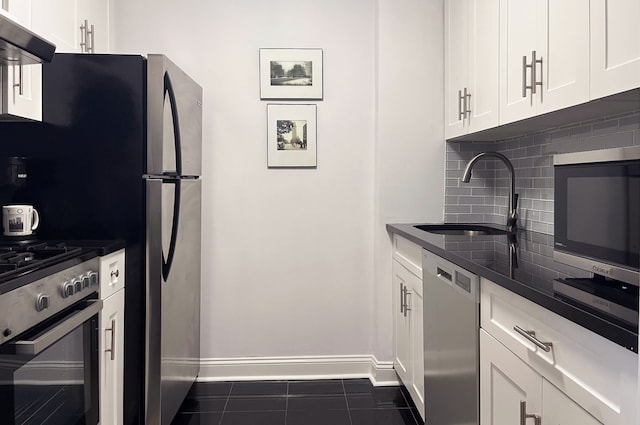 kitchen featuring a sink, under cabinet range hood, appliances with stainless steel finishes, dark countertops, and backsplash