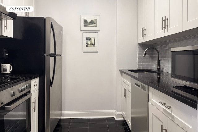 kitchen featuring a sink, dark countertops, white cabinetry, stainless steel appliances, and decorative backsplash