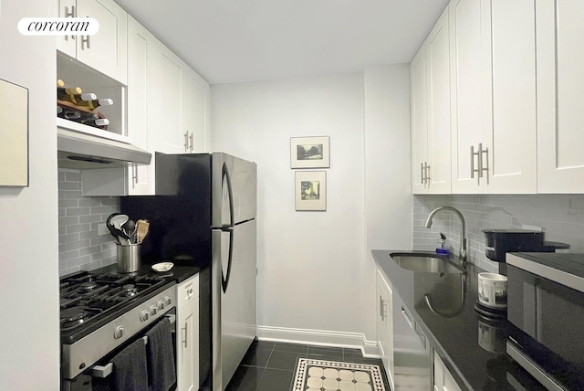 kitchen with a sink, stainless steel range with gas cooktop, tasteful backsplash, dishwasher, and dark tile patterned flooring