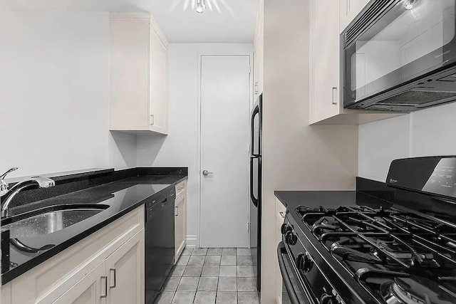 kitchen featuring light tile patterned floors, dark stone counters, a sink, black appliances, and white cabinetry