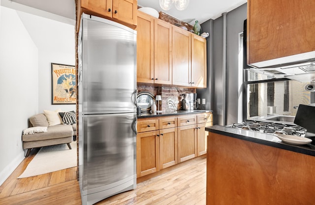 315 E 12th St Unit 22, New York City, NY 10003 - kitchen with stainless steel fridge, light wood finished floors, dark countertops, and backsplash