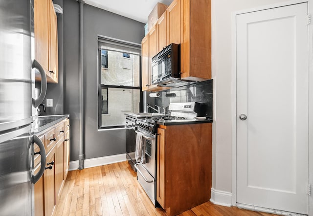 315 E 12th St Unit 22, New York City, NY 10003 - kitchen featuring baseboards, light wood-type flooring, stainless steel appliances, and tasteful backsplash
