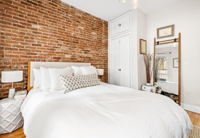 315 E 12th St Unit 22, New York City, NY 10003 - bedroom with baseboards, wood finished floors, and brick wall