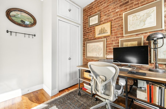 315 E 12th St Unit 22, New York City, NY 10003 - home office with baseboards, light wood finished floors, and brick wall