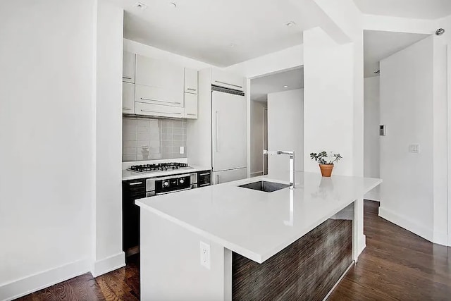 kitchen with oven, paneled fridge, a sink, backsplash, and stainless steel gas stovetop