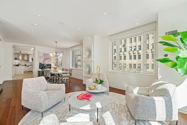 living area with baseboards, wood finished floors, recessed lighting, and a chandelier