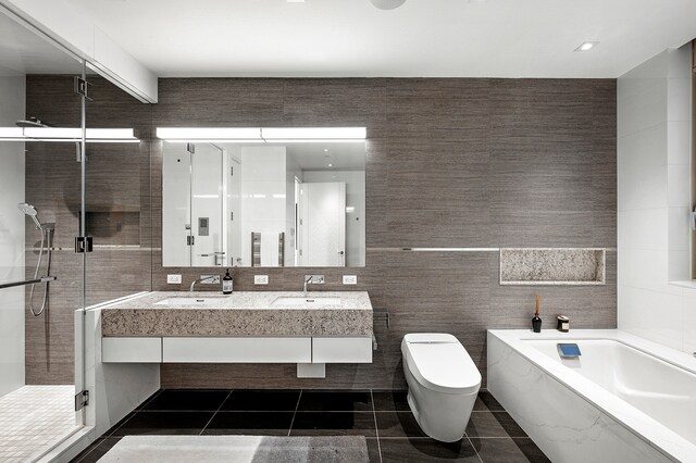 full bathroom featuring a shower stall, a sink, and tile walls