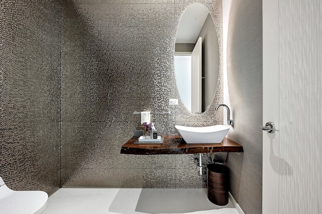 half bathroom with a sink, backsplash, and toilet