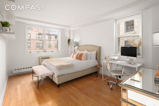 bedroom with light wood finished floors, multiple windows, a wall mounted air conditioner, and a baseboard radiator