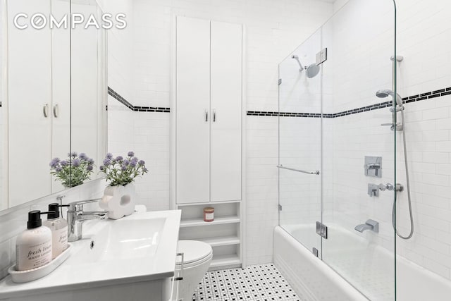 bathroom featuring tile patterned flooring, toilet, vanity, and bath / shower combo with glass door