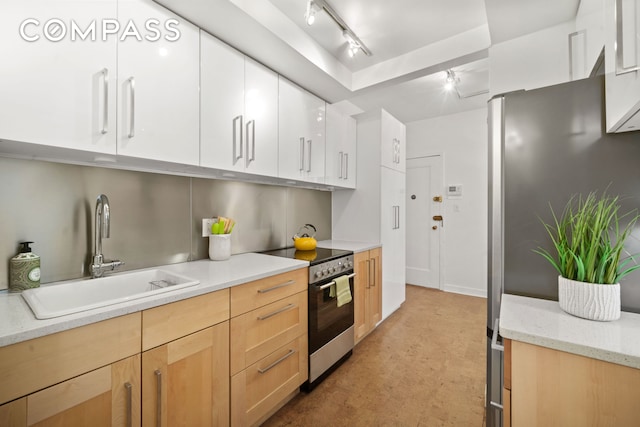 kitchen featuring light stone counters, concrete floors, stainless steel appliances, a sink, and white cabinets