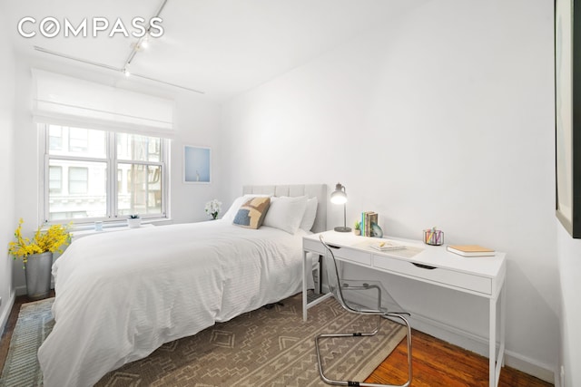 bedroom with track lighting, baseboards, and wood finished floors