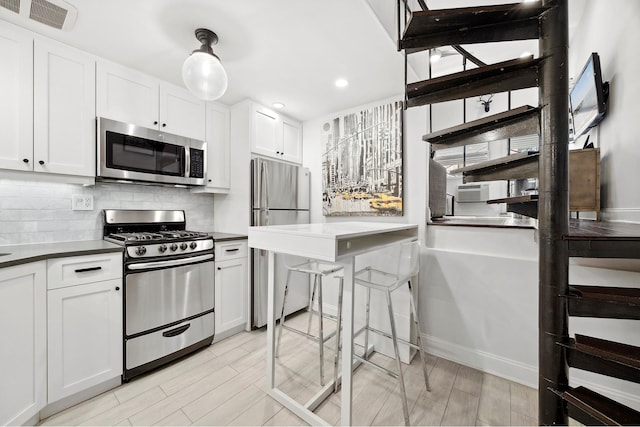 kitchen with dark countertops, visible vents, backsplash, appliances with stainless steel finishes, and white cabinetry