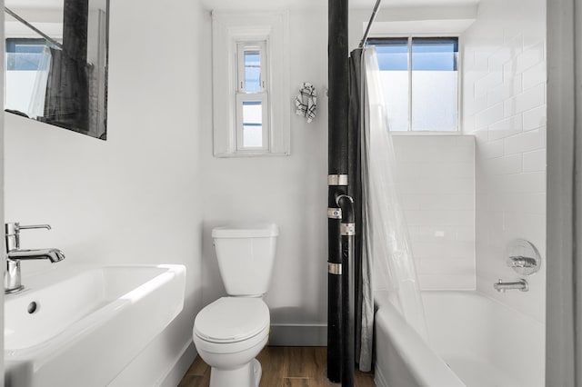 bathroom featuring baseboards, toilet, shower / tub combo, wood finished floors, and a sink
