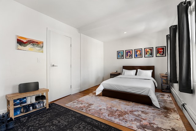 bedroom with a baseboard heating unit and wood finished floors
