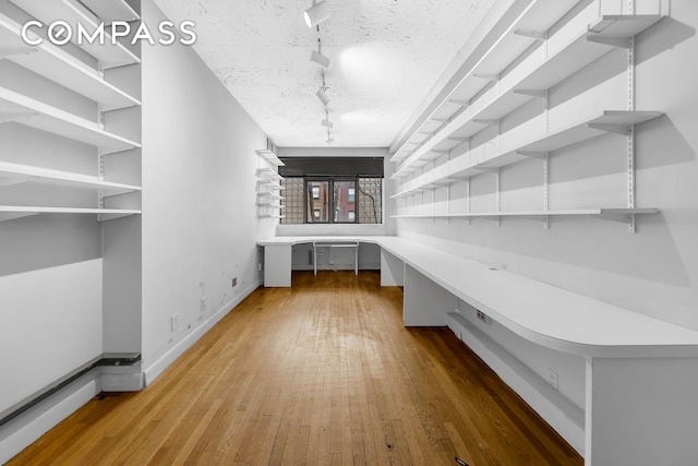 219 E 49th St, New York City, NY 10017 - unfurnished office with track lighting, baseboards, hardwood / wood-style floors, and built in study area