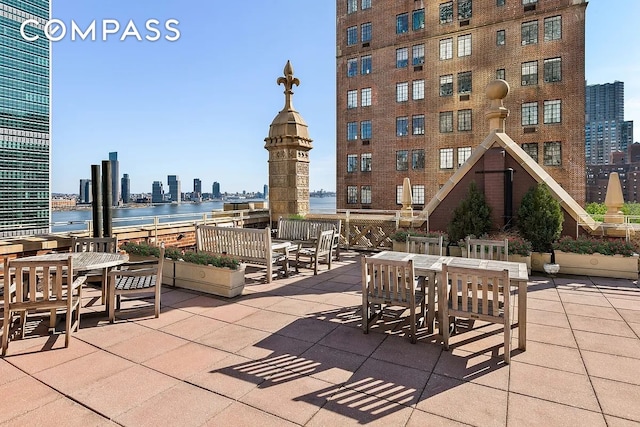 view of patio / terrace with a view of city, a water view, and outdoor dining space