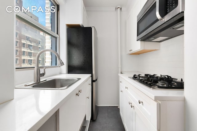 kitchen featuring a sink, appliances with stainless steel finishes, white cabinets, and dark tile patterned flooring