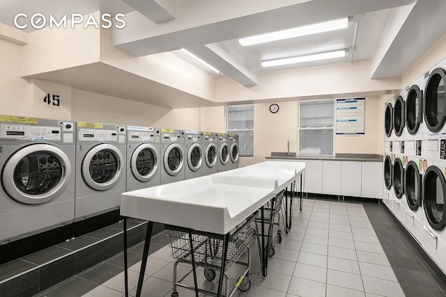 community laundry room featuring dark tile patterned flooring, stacked washer / dryer, and washer and dryer