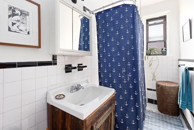 221 E 18th St Unit 6H, New York City, NY 11226 - full bathroom with tile walls, vanity, wainscoting, and a shower with shower curtain