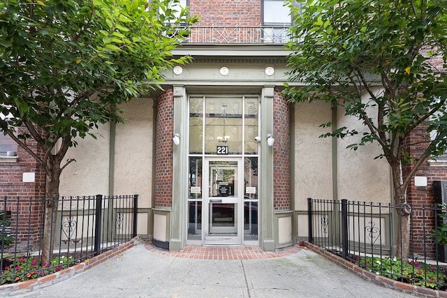 221 E 18th St Unit 6H, New York City, NY 11226 - doorway to property featuring stucco siding, fence, and brick siding