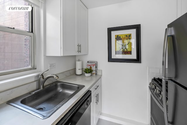 kitchen with white cabinets, appliances with stainless steel finishes, a sink, and light countertops