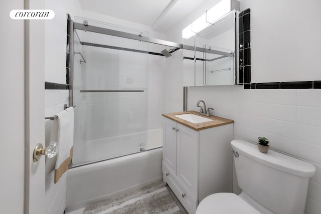 233 E 69th St Unit 6A, New York City, NY 10021 - full bathroom featuring toilet, bath / shower combo with glass door, vanity, and tile walls