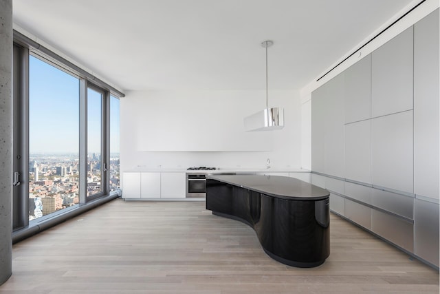 kitchen with a wall of windows, stainless steel appliances, light wood-style floors, modern cabinets, and a center island