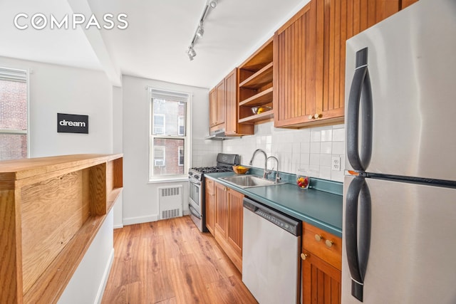 kitchen featuring tasteful backsplash, open shelves, a sink, stainless steel appliances, and light wood-style flooring