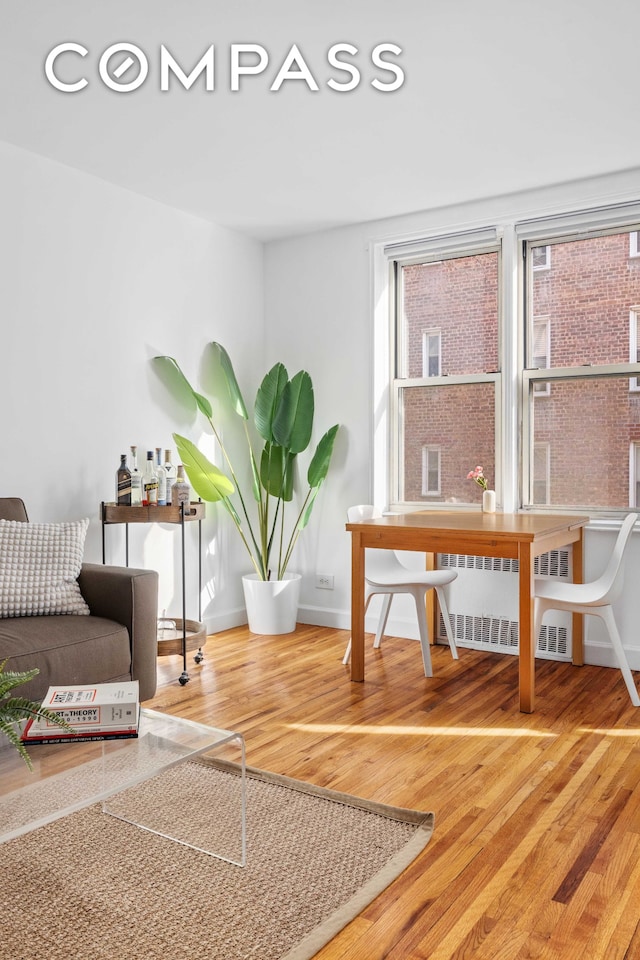 living area with baseboards, radiator, wood finished floors, and a healthy amount of sunlight