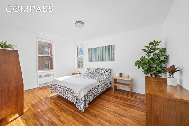 bedroom with hardwood / wood-style flooring, baseboards, and radiator