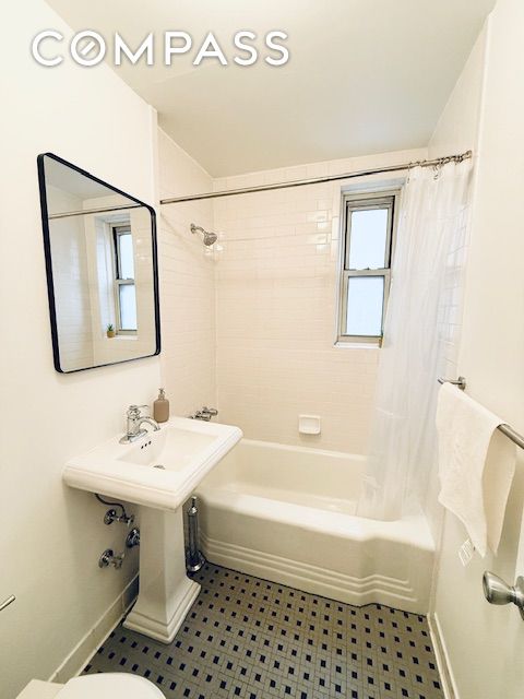 bathroom featuring toilet, baseboards, and shower / bath combination with curtain