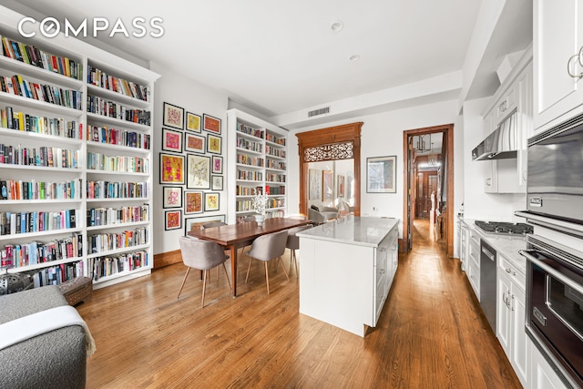 kitchen featuring light wood-type flooring, visible vents, light stone countertops, and white cabinetry