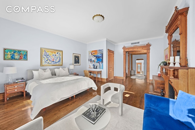 bedroom featuring visible vents, crown molding, baseboards, and wood finished floors