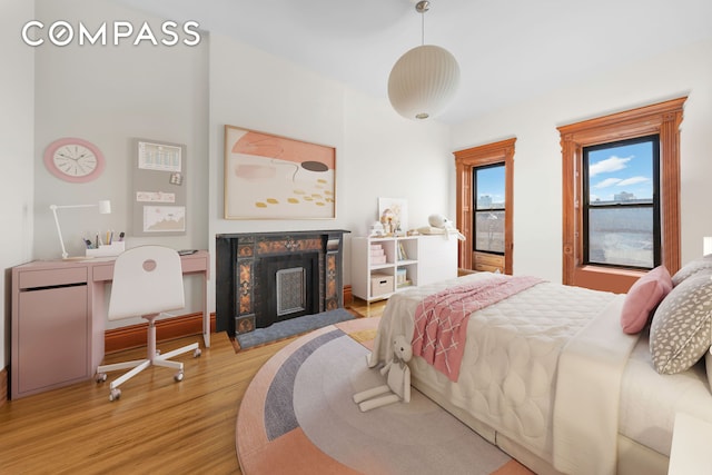 bedroom featuring a fireplace with flush hearth and wood finished floors