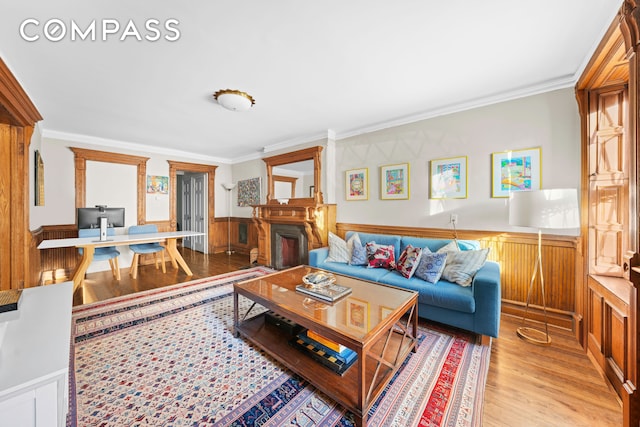 living area featuring a wainscoted wall, crown molding, and wood finished floors