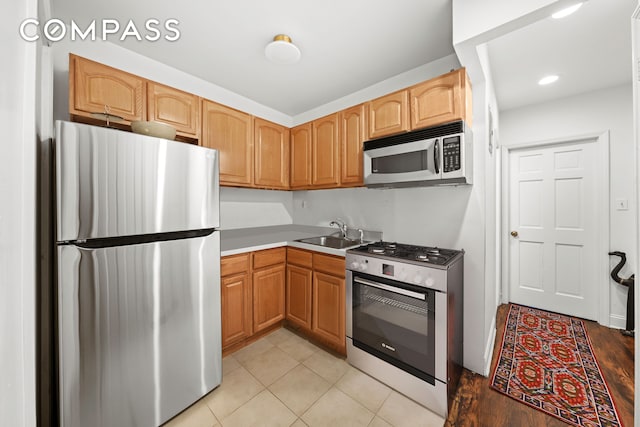 kitchen with a sink, stainless steel appliances, recessed lighting, and light tile patterned floors