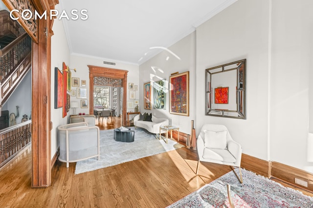 living room with visible vents, baseboards, wood finished floors, and ornamental molding