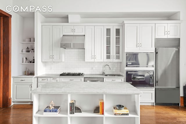 kitchen with under cabinet range hood, a sink, appliances with stainless steel finishes, and open shelves