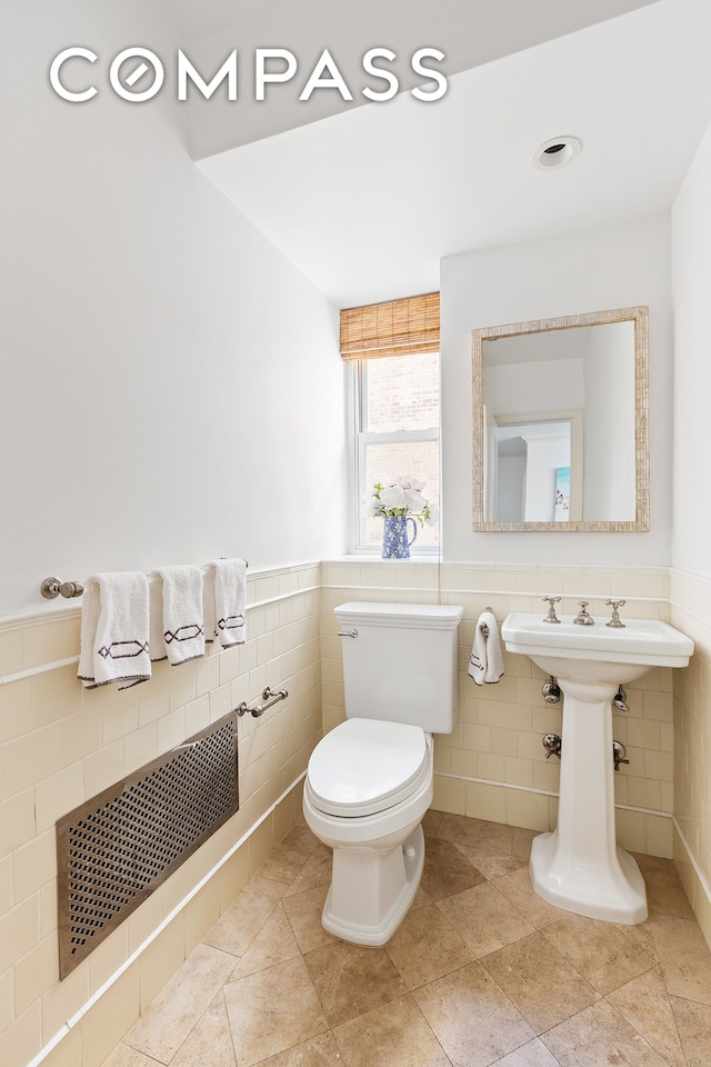 135 E 71st St Unit 9D, New York City, NY 10021 - half bath featuring tile walls, toilet, and a wainscoted wall